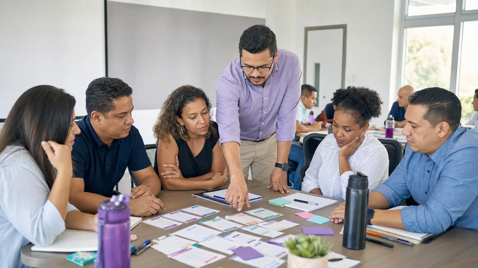 A facilitator leads a diverse group of adults through a hands-on team workshop.