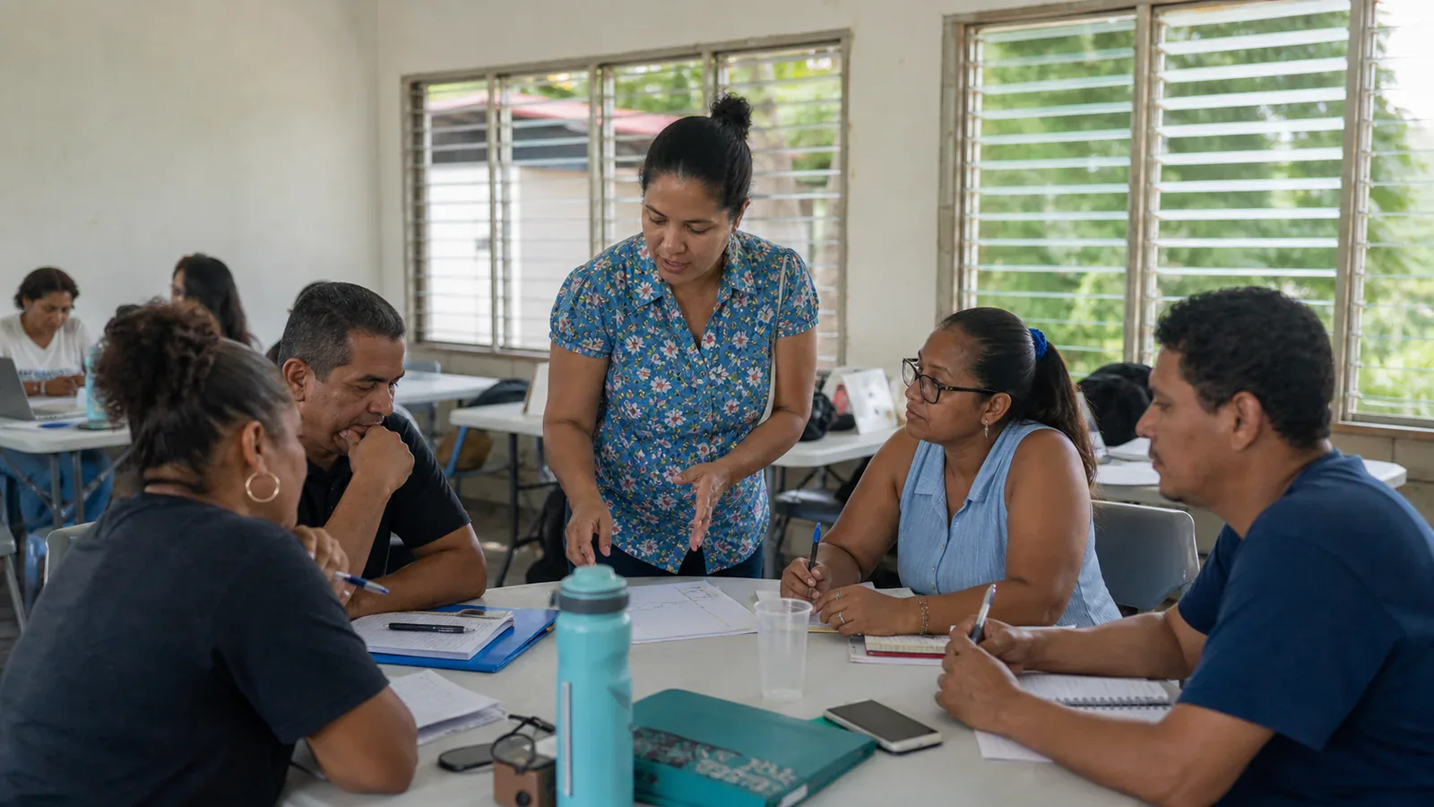 A facilitator guides adult learners through a practical group exercise in a community training room.