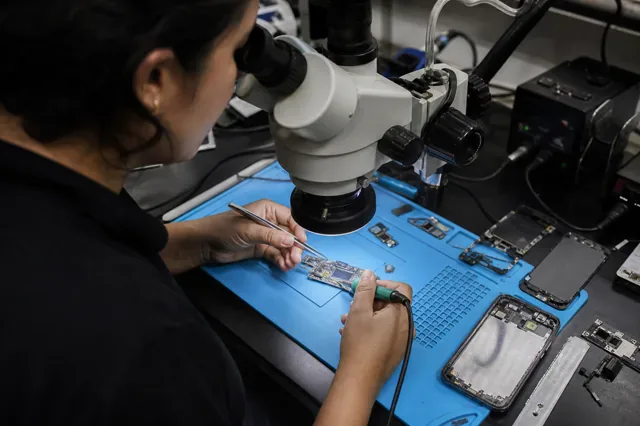 Técnica repara bajo microscopio la placa de un teléfono desmontado.