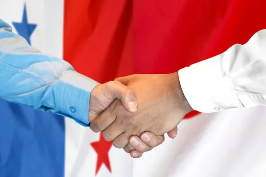 Two people shaking hands in front of the Panama flag, symbolizing agreement or cooperation.