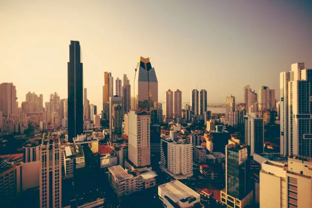 Aerial view of Panama City at sunset, featuring skyscrapers and a golden sky.
