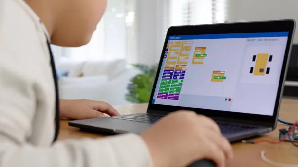 Child using a laptop for block-based coding, programming a virtual robot.