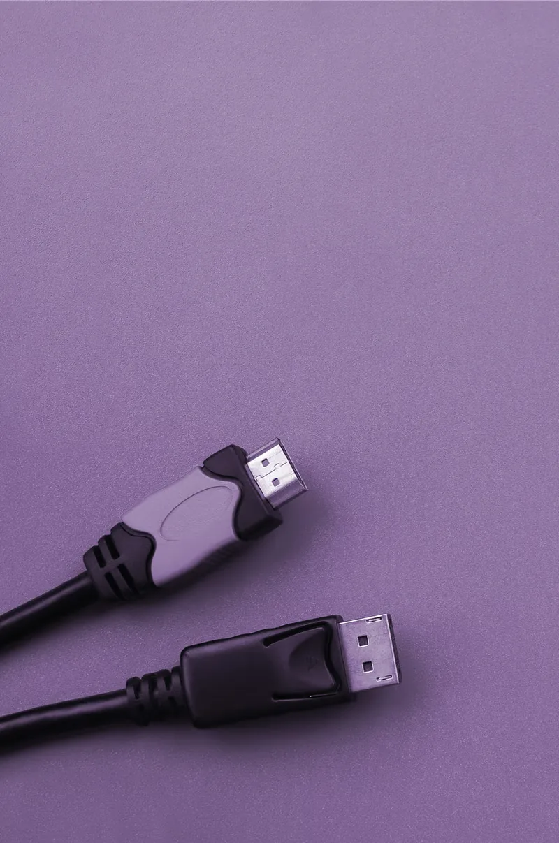 Two DisplayPort cables, one gray and one black, on a purple background.